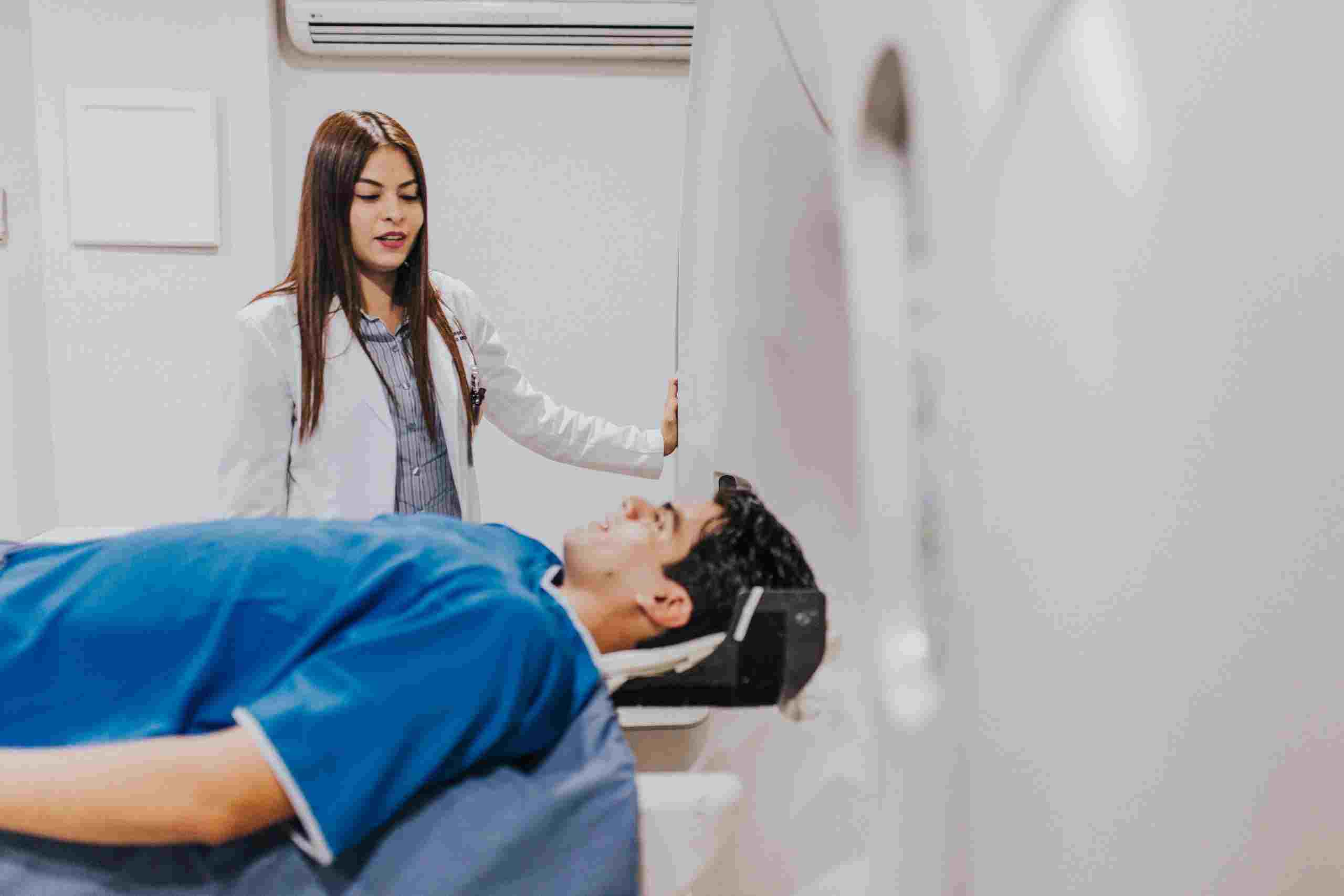 Medical imaging room with a healthcare professional assisting a patient during a diagnostic scan, illustrating Orthopedic Hospital Financing, Behavioral Health Hospital Funding, Healthcare Debt Financing, Hospital Infrastructure Loans, and Healthcare System Financing for modern healthcare facilities.