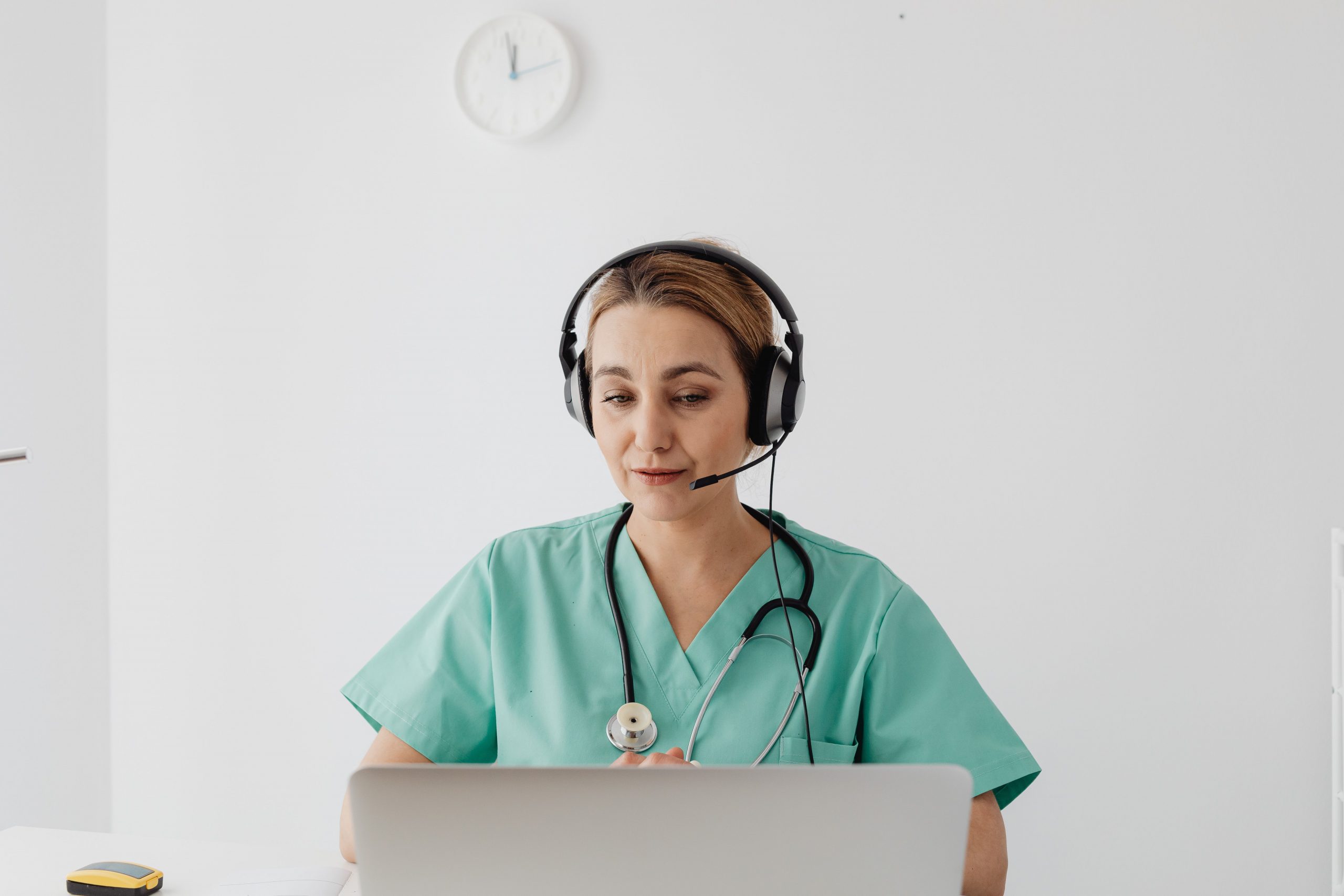 Healthcare professional conducting a virtual consultation while using a laptop and headset in a modern medical office, representing Medical Billing Financing, Diagnostic Imaging Equipment Financing, Funding for Medical Clinics, Ophthalmology Practice Financing, and Physician Office Startup Financing for healthcare practice growth, technology upgrades, and operational expansion.
